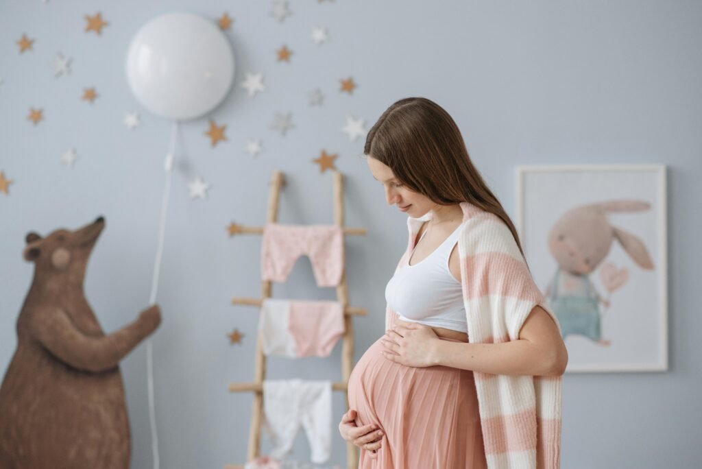 Side view of expectant mother in a cozy nursery with soft pastel decor.
