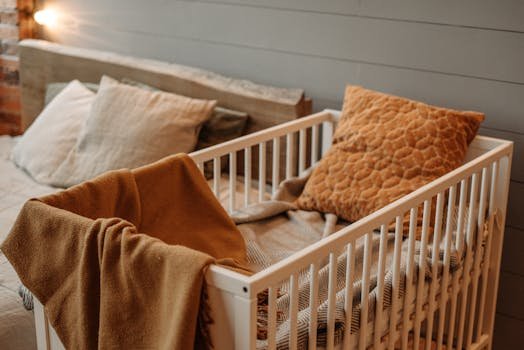 A cozy bedroom featuring a white crib with warm blankets and pillows, creating a comfortable ambiance.